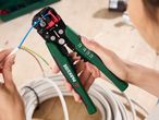 A person using Parkside wire strippers to strip the insulation from electrical wires.