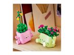 Two colorful toy plant pots with faces, one pink with yellow flowers, one green with pink flowers.
