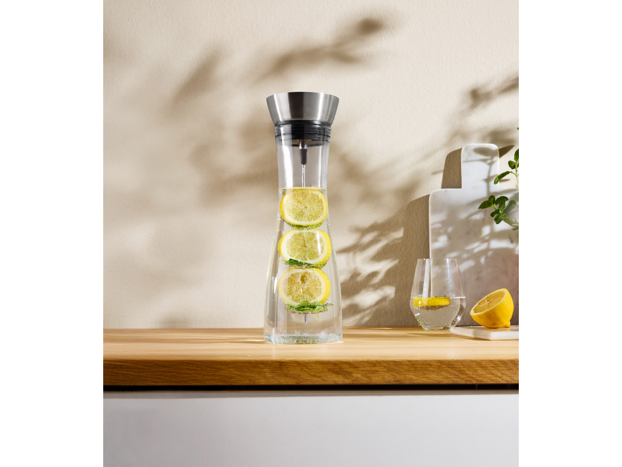 SILVERCREST Wasserkaraffe mit Zitrone und Minze, Glas und geschnittene Zitrone auf Holz.
