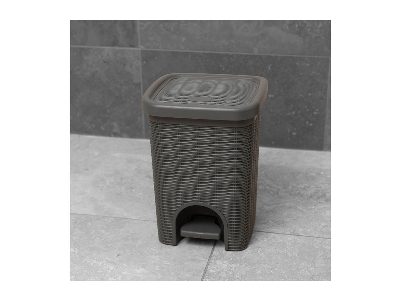A dark grey plastic step-on trash can.