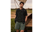 Model purtând o cămașă imprimată și pantaloni scurți verzi în aer liber.