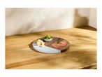Round serving board with cheese cubes, olives, and sliced meat on a wooden surface.