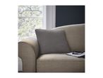 A cozy sofa with a grey cushion, glasses, and a book, by a window with green trees.