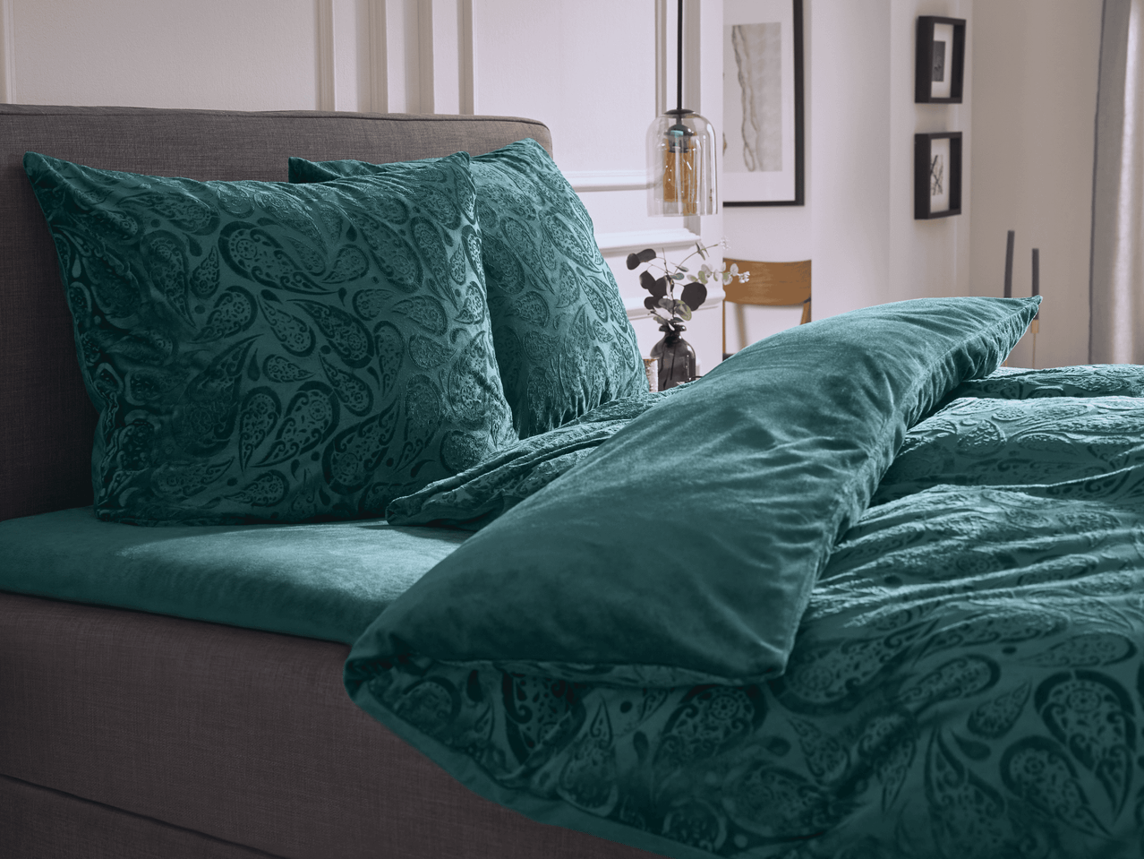 Bett mit tealfarbenen Kissen und Bettwäsche mit Paisleymuster