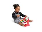 Happy baby playing with a colorful toy piano with sheet music.