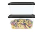 Two stacked rectangular food containers with black lids, one filled with pasta salad.