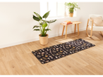 A black mushroom-patterned runner rug on a light wood floor in a bright room.
