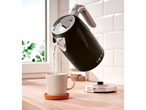 Black Silvercrest® kettle pouring water into a mug on a wooden countertop.