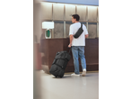 Man with a black duffel bag and a black crossbody bag at a hotel reception.