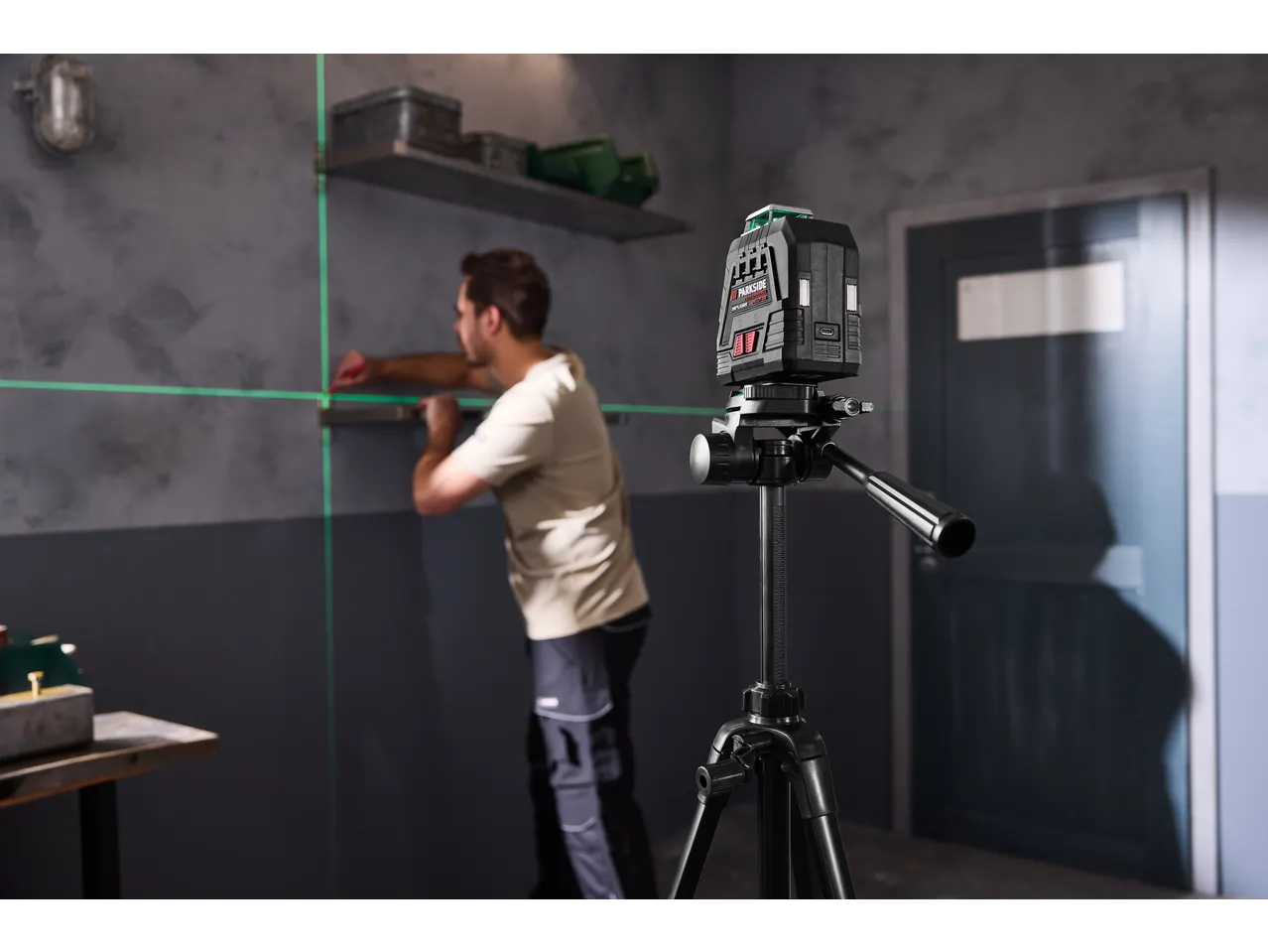 Laser de linhas cruzadas PARKSIDE PERFORMANCE com tripé, usado por um homem.