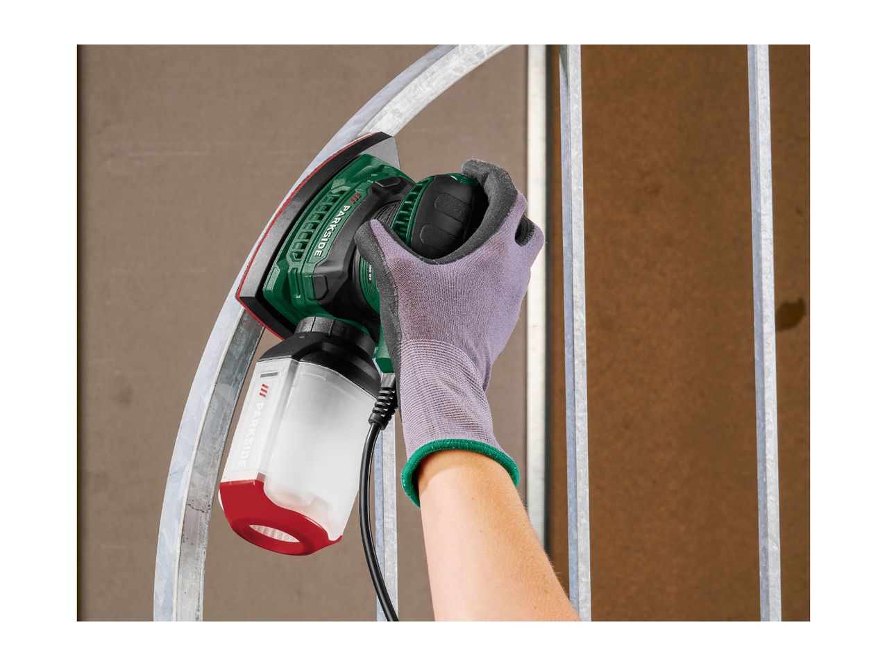Handheld sander with dust collection box sanding a curved metal bar