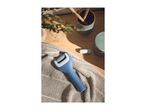 Blue electric foot file on a towel with bathroom accessories in the background.