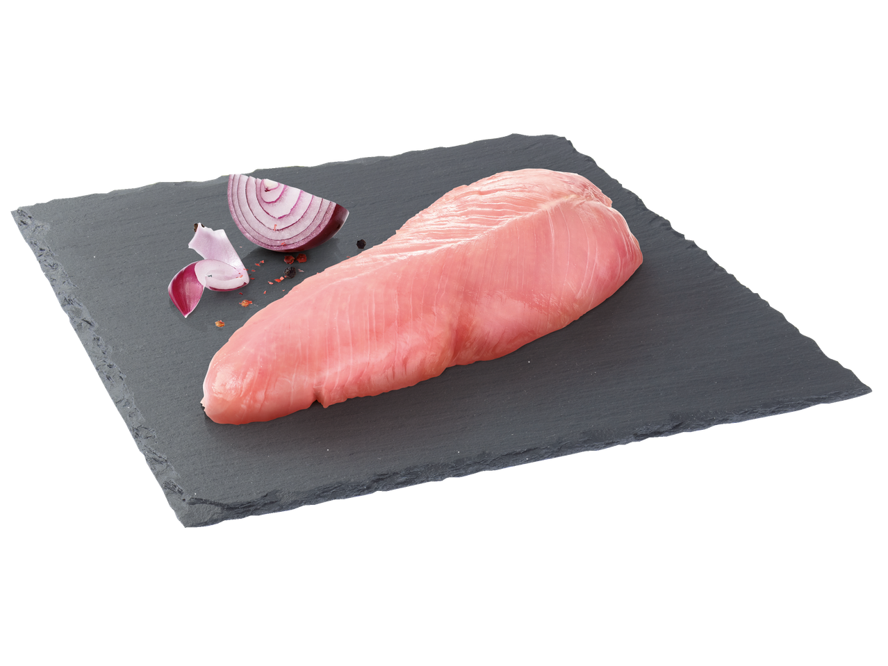 Filé de peito de peru cru em uma pedra ardósia com cebola roxa fatiada e temperos.