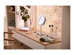 Vanity table with makeup, brushes, mirror, and a plant, next to a window with blinds.