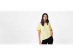 Model v rumeni majici in črnih hlačah.