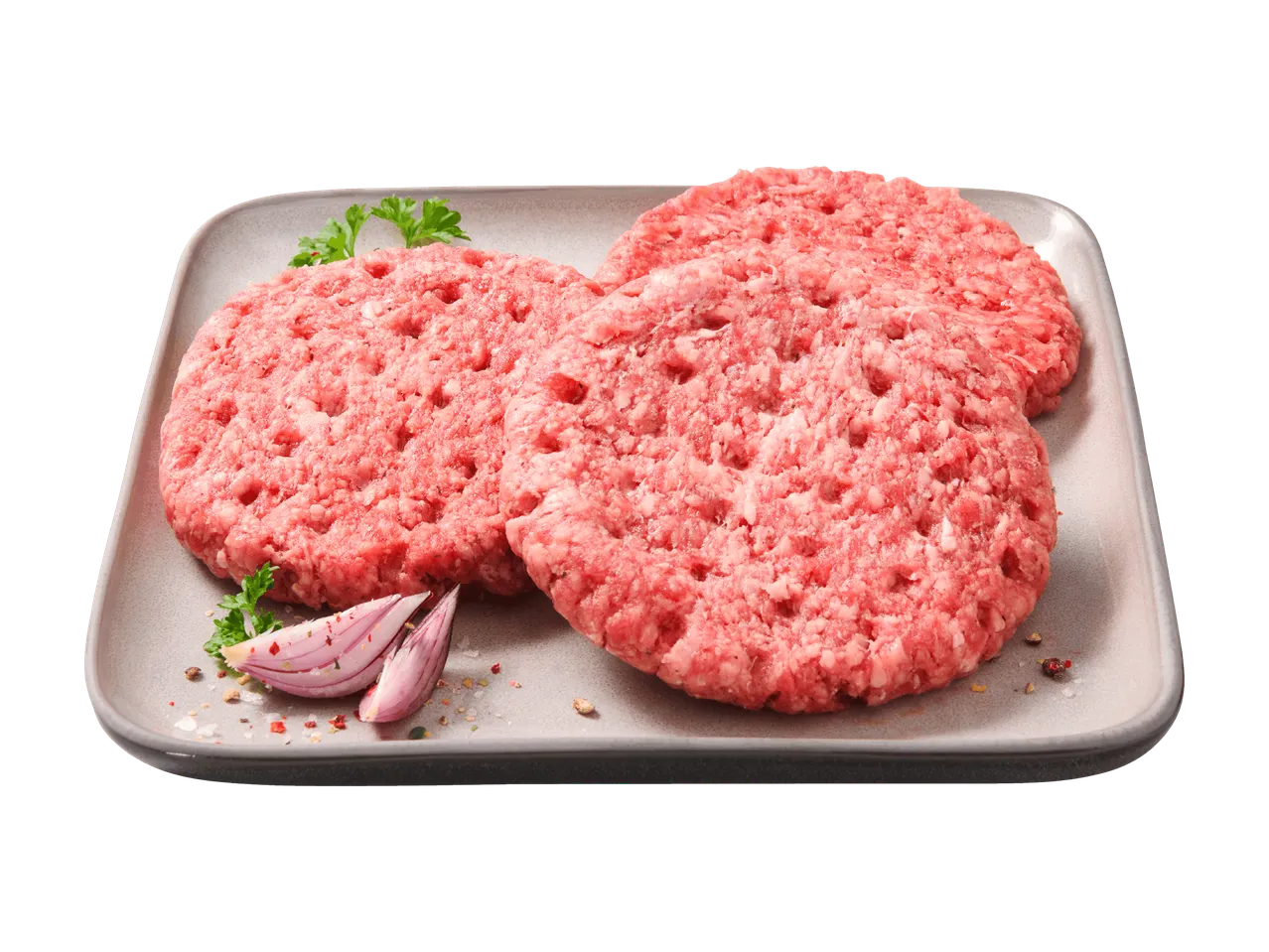 Trois steaks hachés crus sur un plateau gris, garnis de persil et d'oignon rouge.