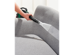 Cleaning a gray sofa with a cleaning machine.