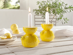 Deux bougeoirs en forme de citron avec des bougies blanches.