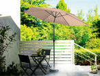 Guarda-sol bege, conjunto de mesa e cadeiras de jardim.
