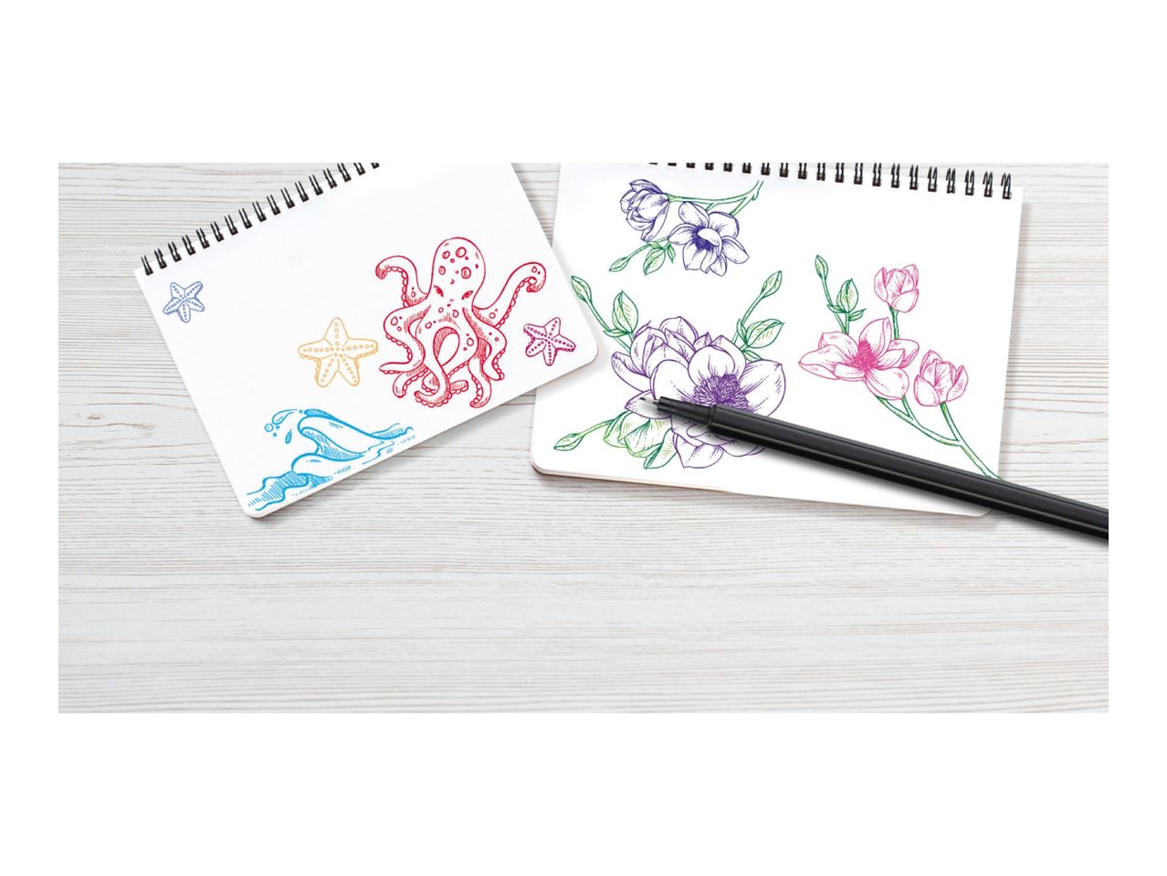 Two sketchbooks with colorful drawings of sea creatures and flowers, with a black pen.