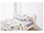 A bed with floral duvet cover and pillows, and a white nightstand.