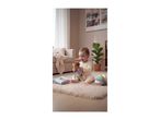 Happy baby playing with a soft toy, a soft book, and a fabric ball on a rug.
