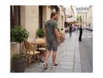 Man in a green t-shirt with a palm tree graphic and grey shorts walking on a city street.