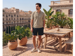 Homem de polo e calções num terraço com vista para a cidade.