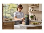 Woman making green juice with a juicer in a modern kitchen.