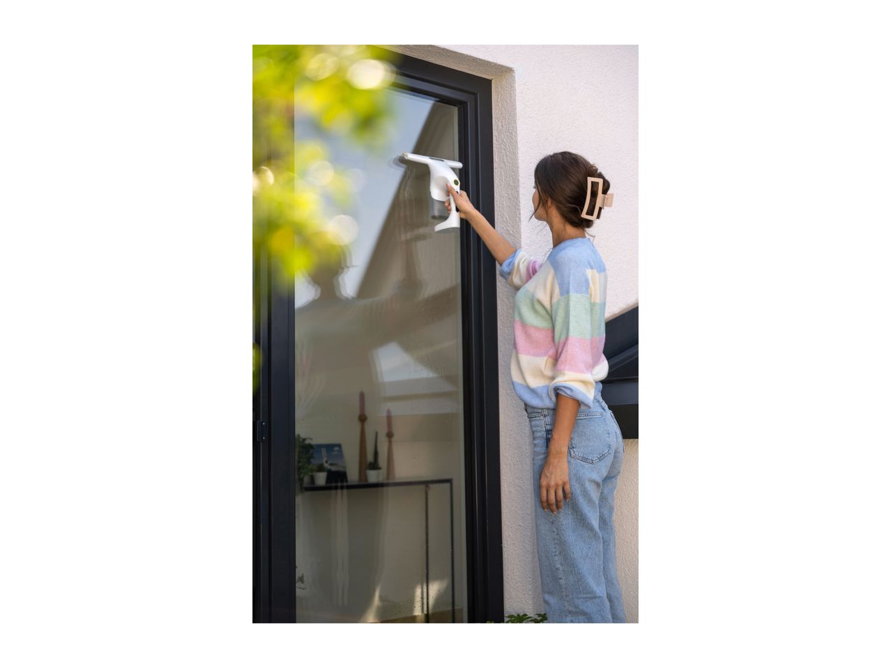 Woman cleaning a window with a window vacuum cleaner.