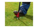 Person using a weed puller tool to remove a weed from a green lawn.