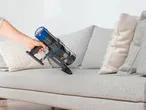 CLEANMAXX kézi porszívóval tisztítanak egy világos kanapét.