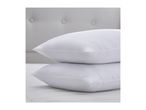 Two white pillows stacked on a mattress with a tufted headboard in the background.