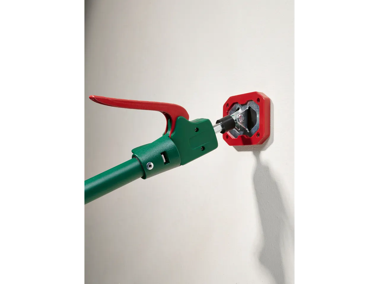 Suporte de teto PARKSIDE® com alça vermelha e haste verde, conectado a uma base de parede vermelha.