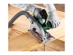 Close-up of a person wearing grey gloves using a circular saw with a dust extraction hose to cut a wooden plank.