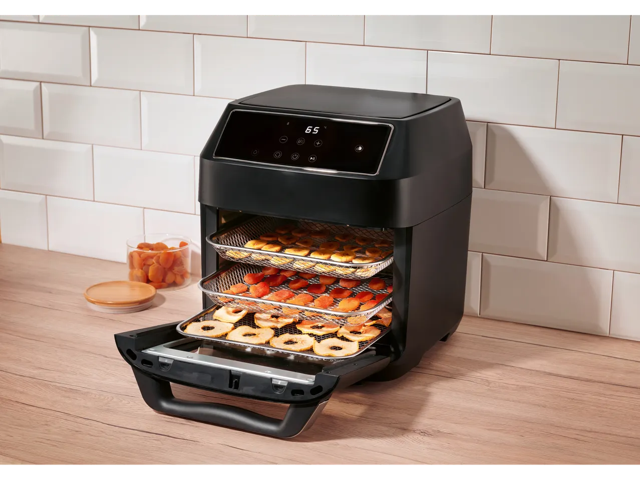 Black air fryer with digital display dehydrating fruit.