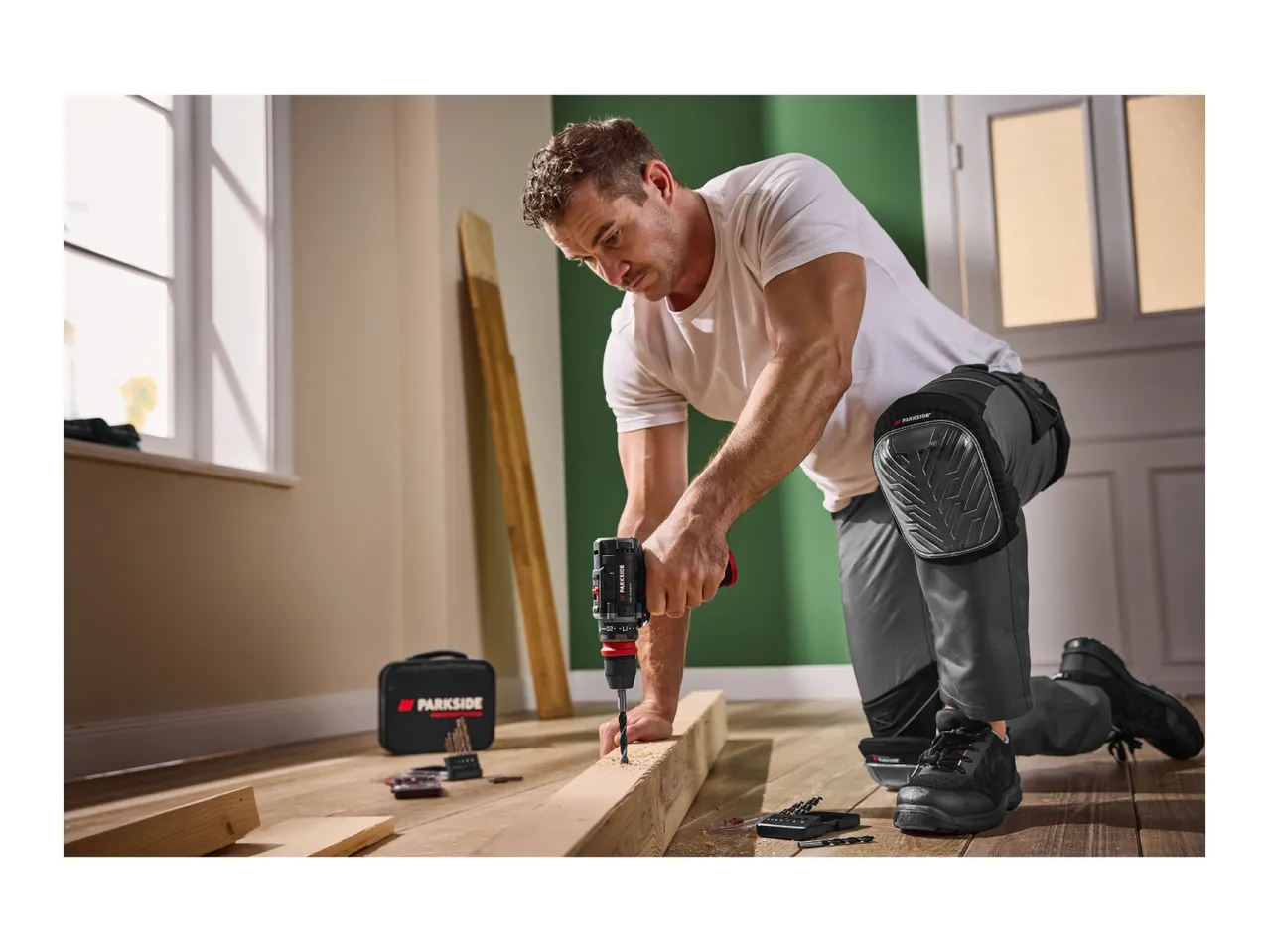 Man using a Parkside cordless drill to work on wood, wearing Parkside knee pads.