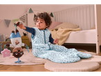 Baby in a cute light blue polka dot sleep sack plays with a plush toy.