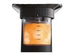 Close-up of a black milk frother with a transparent container filled with orange liquid, showing volume markings.