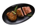 Filet mignon z rožmarinom in morsko soljo na črnem ovalnem krožniku.
