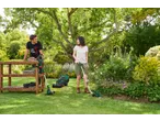 Man and woman with Parkside® grass trimmer and lawnmower in a garden.