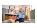 Happy baby in blue clothes playing on a rug with a colorful ball and rainbow picture.