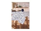 White tablecloth with blue leaf pattern on a dining table set with plates and candles.