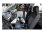 Man cleaning car interior with a wet and dry vacuum cleaner and a handheld upholstery cleaner.