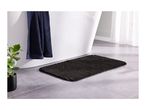 Dark grey bath mat on a tiled floor next to a white bathtub with a navy towel.