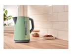 A green SilverCrest electric kettle on a wooden counter with cookies and a jar of sugar.