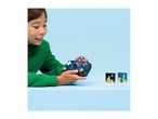Child playing with a blue toy handheld game console, with two pixel art blocks on a table.