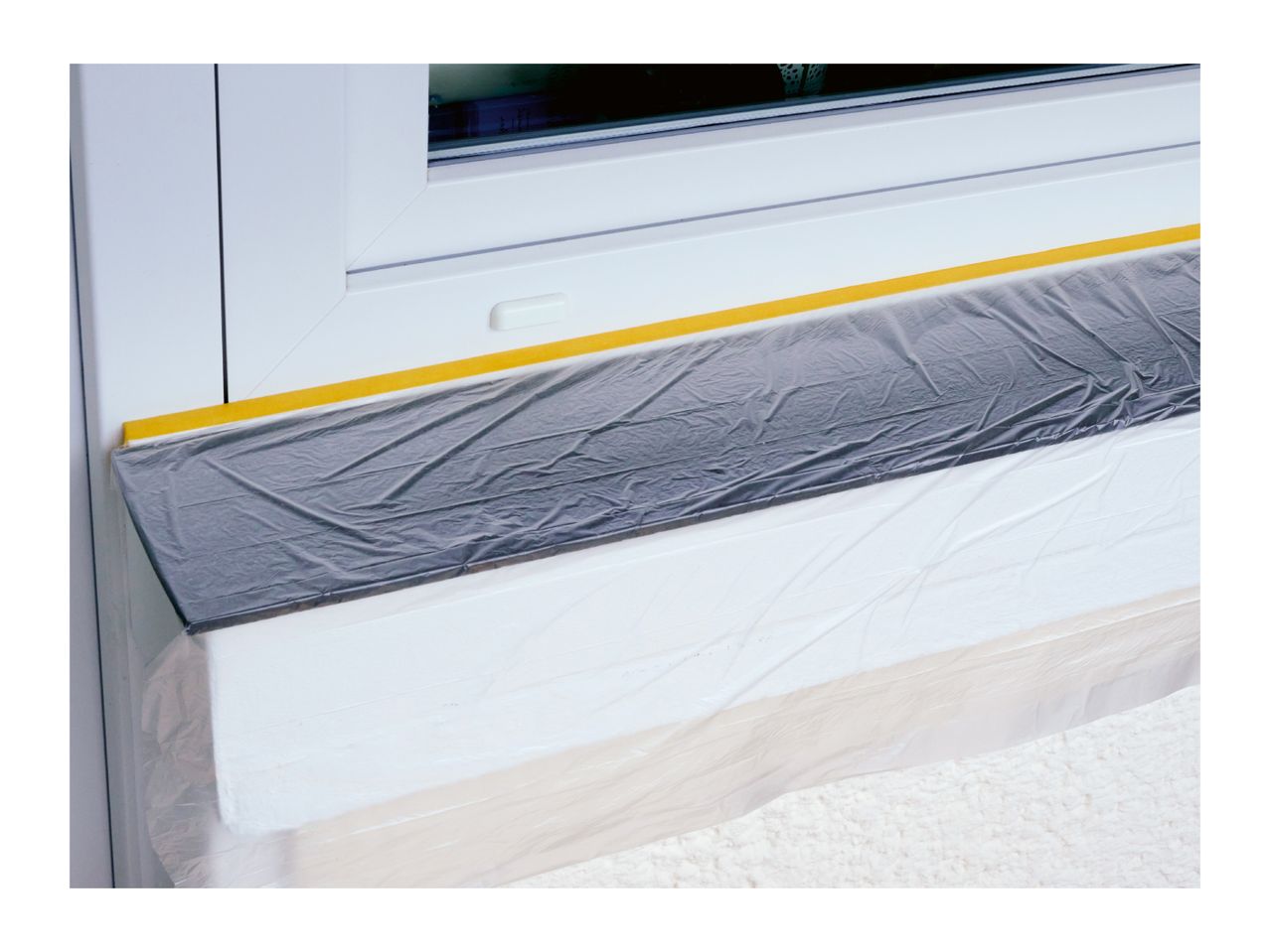 Window protected with masking tape and plastic sheeting for painting or renovation.