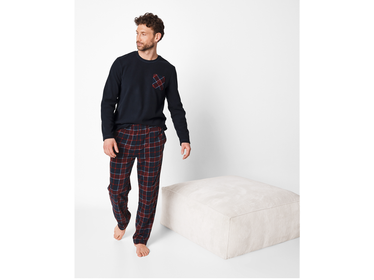 Man in a navy long-sleeved top with a plaid pocket and plaid pajama pants.