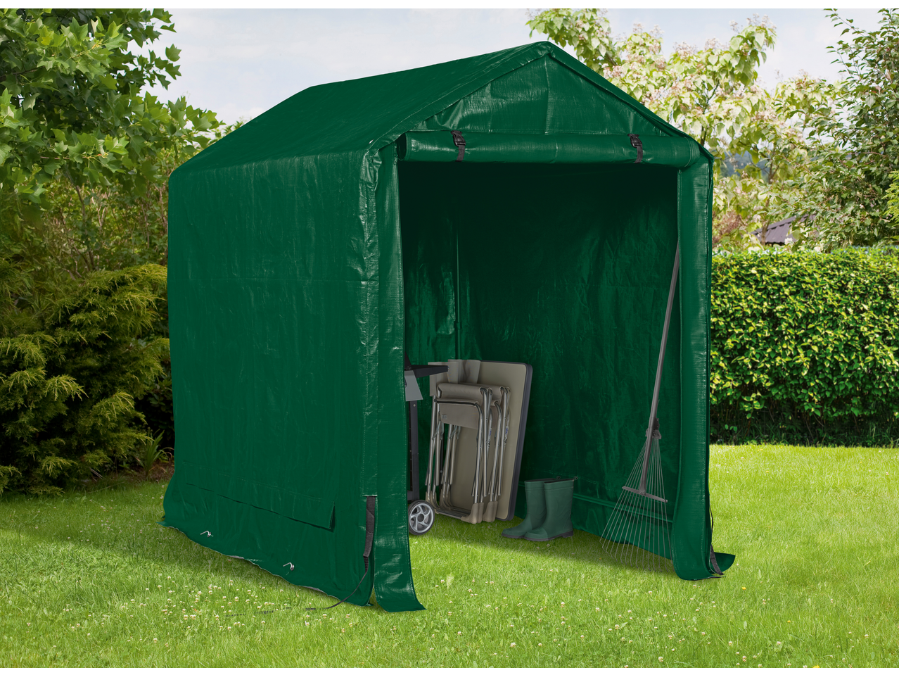 Green garden storage tent with garden tools and folding chairs inside on a lawn.